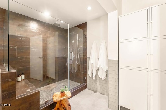 bathroom with a shower stall and tile walls