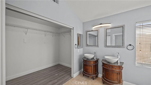 bathroom with two vanities, a sink, visible vents, and baseboards