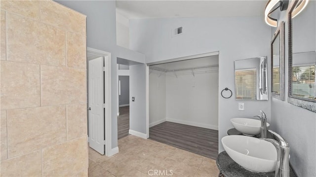 full bath featuring visible vents, lofted ceiling, tile patterned flooring, a spacious closet, and a sink