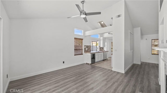 unfurnished living room featuring a ceiling fan, wine cooler, baseboards, and wood finished floors