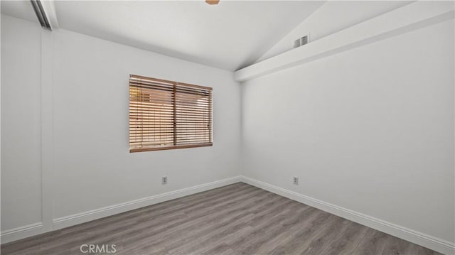 unfurnished room with lofted ceiling, visible vents, baseboards, and wood finished floors