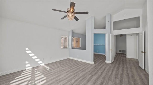 unfurnished room with lofted ceiling, ceiling fan, wood finished floors, visible vents, and baseboards