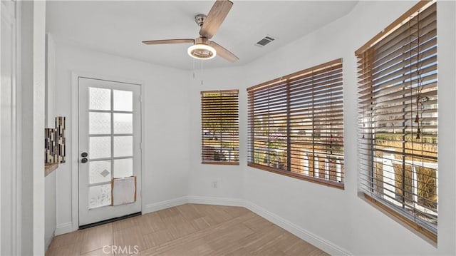 doorway to outside featuring a ceiling fan, visible vents, light wood-style flooring, and baseboards