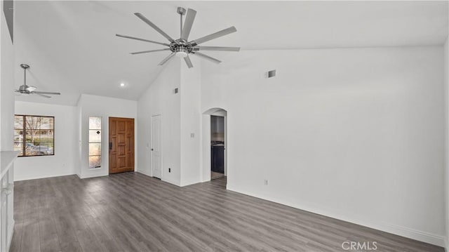 unfurnished living room featuring dark wood-type flooring, arched walkways, ceiling fan, and high vaulted ceiling