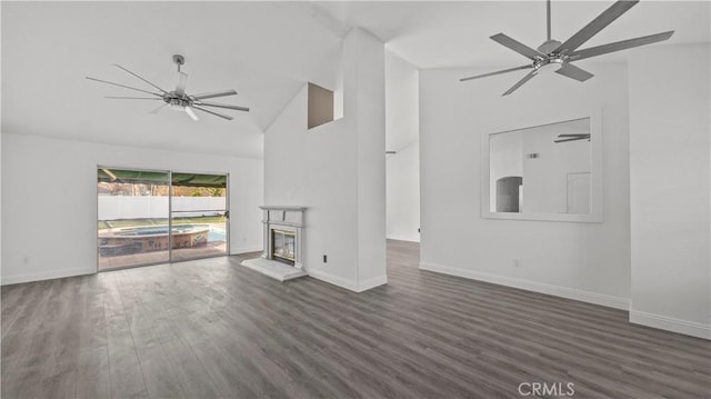 unfurnished living room with ceiling fan, a glass covered fireplace, dark wood finished floors, and baseboards