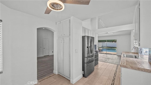 kitchen featuring a ceiling fan, appliances with stainless steel finishes, light countertops, white cabinetry, and a sink