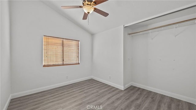 unfurnished bedroom featuring lofted ceiling, a closet, ceiling fan, light wood-type flooring, and baseboards