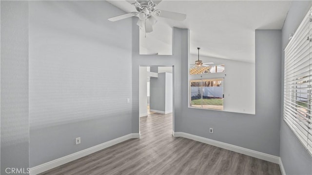 spare room featuring lofted ceiling, ceiling fan, light wood finished floors, and baseboards