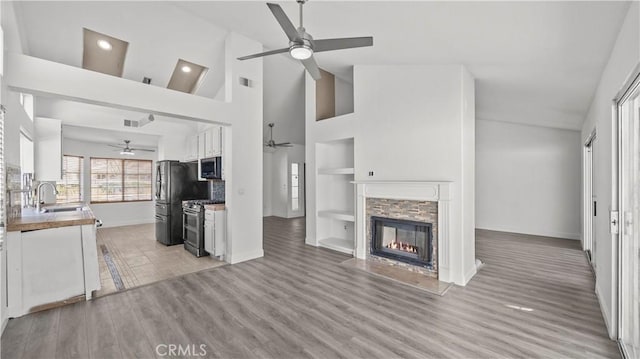 kitchen with white cabinets, appliances with stainless steel finishes, built in shelves, a fireplace, and a sink