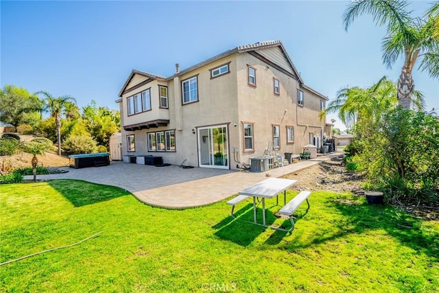 rear view of property featuring a lawn, a jacuzzi, cooling unit, a patio area, and stucco siding