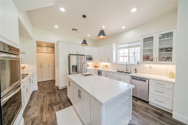 kitchen with a center island with sink, white cabinets, glass insert cabinets, stainless steel appliances, and a sink