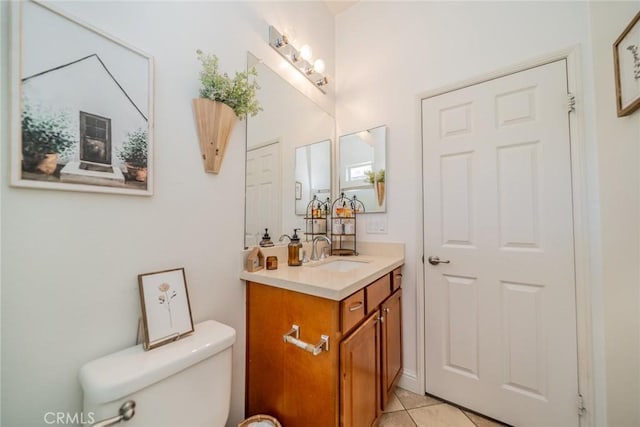 half bathroom with toilet, vanity, and tile patterned floors