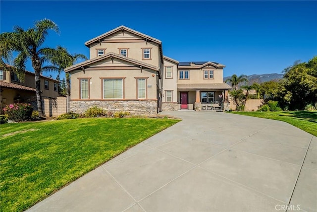 view of front of property with fence, stone siding, roof mounted solar panels, stucco siding, and a front yard