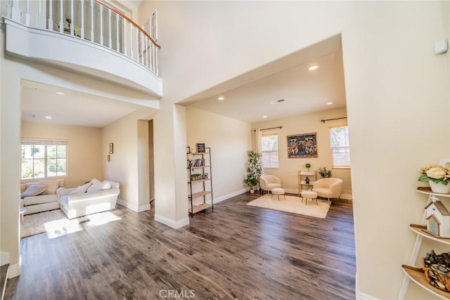 entrance foyer with a high ceiling, wood finished floors, a wealth of natural light, and baseboards