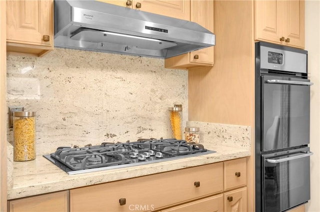 kitchen with under cabinet range hood, tasteful backsplash, double wall oven, and gas cooktop