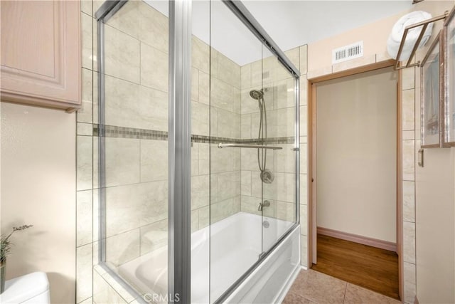 full bath with shower / bath combination with glass door, visible vents, toilet, tile patterned flooring, and baseboards