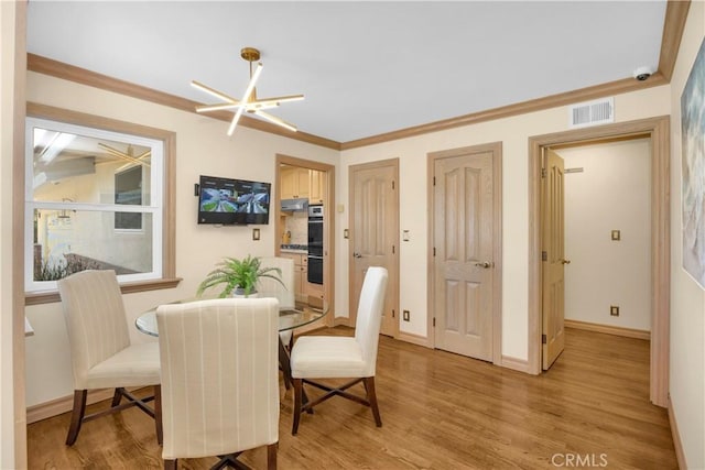 dining area featuring visible vents, baseboards, ornamental molding, light wood finished floors, and an inviting chandelier