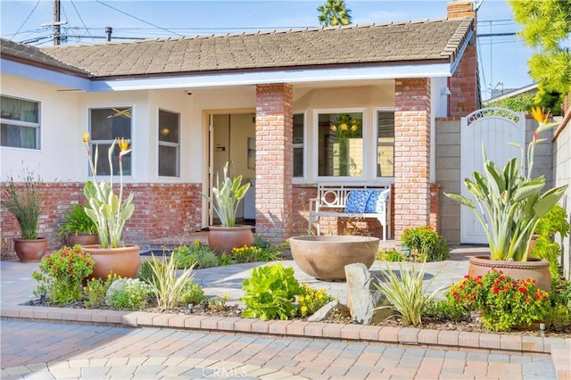 bungalow-style house featuring stucco siding, a chimney, and brick siding