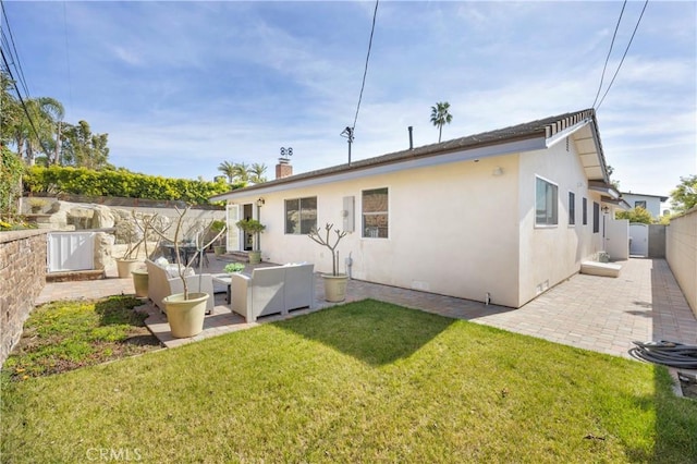 rear view of property with a yard, a patio, a chimney, stucco siding, and a fenced backyard