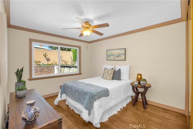 bedroom featuring ceiling fan, baseboards, crown molding, and wood finished floors