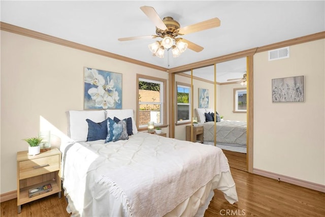 bedroom with visible vents, wood finished floors, and ornamental molding