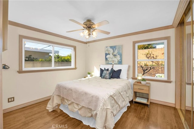 bedroom with a ceiling fan, crown molding, baseboards, and wood finished floors