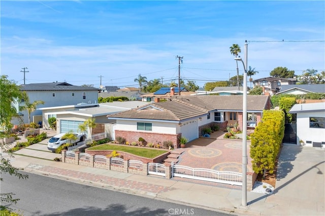 view of front of house featuring a garage, a fenced front yard, a residential view, a gate, and decorative driveway