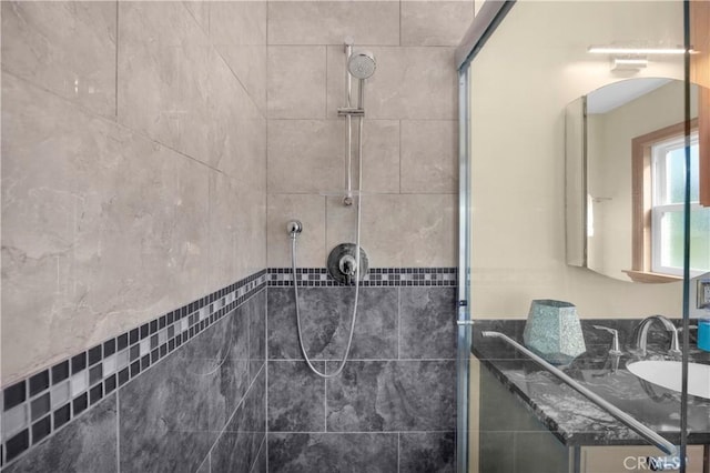 bathroom with a tile shower and vanity