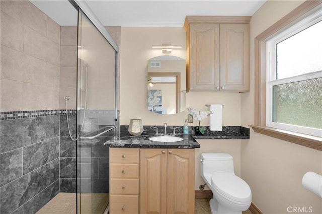 bathroom with a stall shower, visible vents, vanity, and toilet