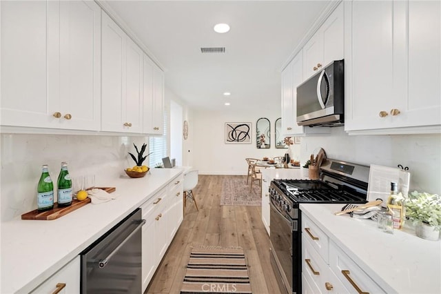 kitchen featuring light wood finished floors, visible vents, backsplash, appliances with stainless steel finishes, and white cabinetry