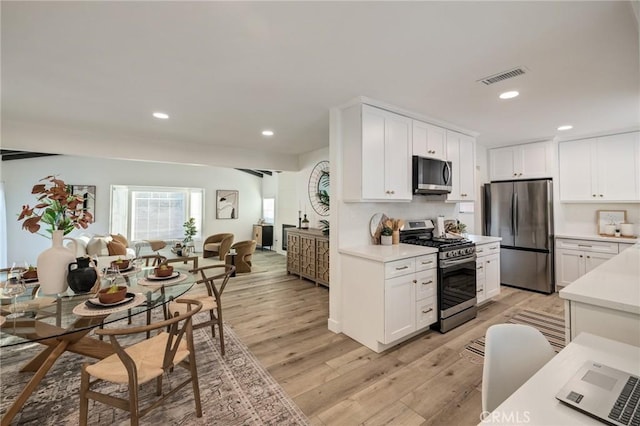 kitchen featuring light countertops, visible vents, appliances with stainless steel finishes, light wood-style floors, and open floor plan