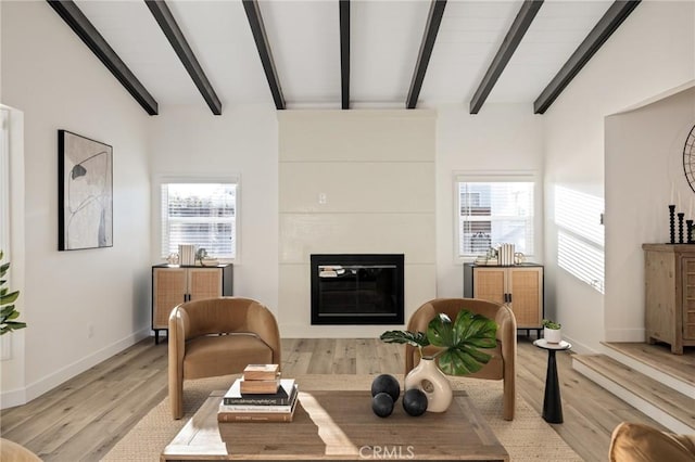 interior space with light wood-type flooring, beam ceiling, a fireplace, and baseboards