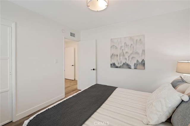 bedroom featuring baseboards, visible vents, and wood finished floors