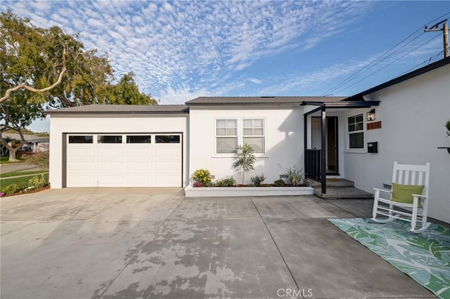 ranch-style house with a garage, driveway, and stucco siding