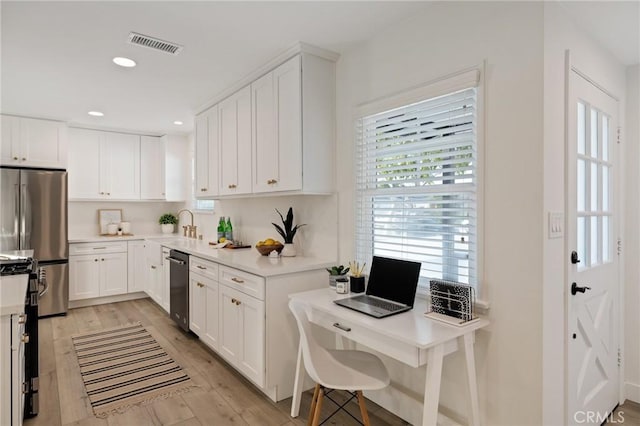 kitchen featuring stainless steel appliances, light countertops, visible vents, white cabinetry, and light wood-type flooring