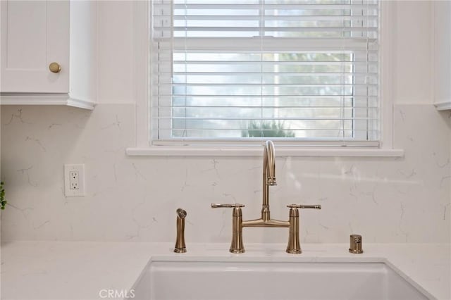 interior details featuring light countertops, white cabinets, a sink, and decorative backsplash