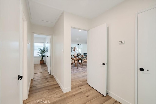 corridor featuring light wood-type flooring and baseboards