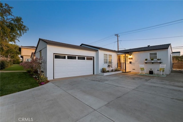 ranch-style house with a garage, concrete driveway, a front yard, and stucco siding