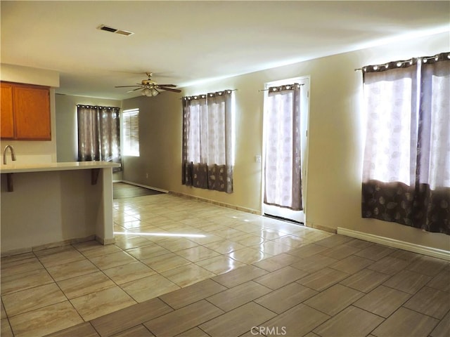 interior space with a wealth of natural light, visible vents, brown cabinets, and light countertops