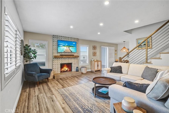 living room featuring recessed lighting, wood finished floors, a tiled fireplace, and stairs