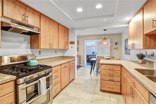 kitchen featuring under cabinet range hood, a tray ceiling, light stone counters, and double oven range