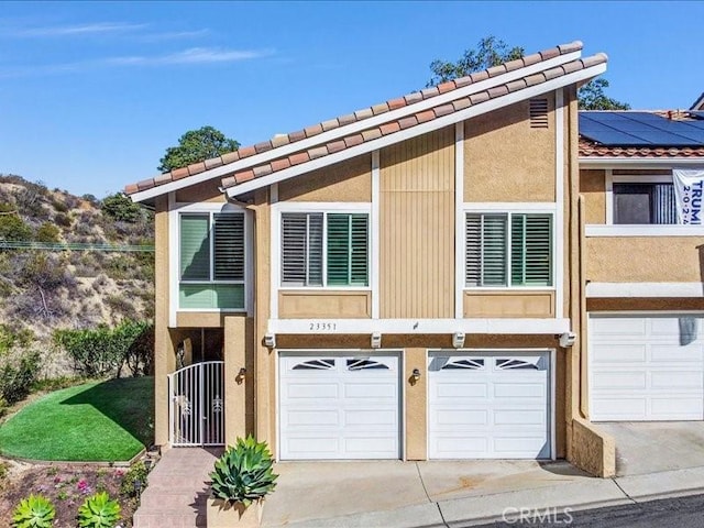 view of front facade with driveway, a garage, solar panels, and stucco siding