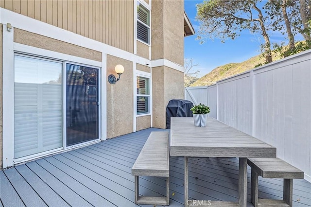 wooden deck featuring a grill, fence, and outdoor dining area