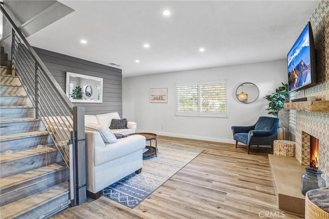 living room with recessed lighting, visible vents, a large fireplace, wood finished floors, and stairs