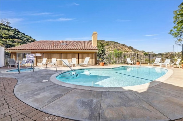 community pool featuring a patio area, fence, and a mountain view