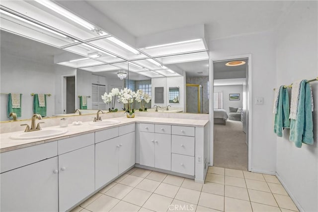 bathroom featuring double vanity, a sink, a shower stall, and tile patterned floors