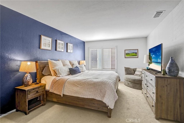 bedroom featuring light carpet, a textured wall, and visible vents