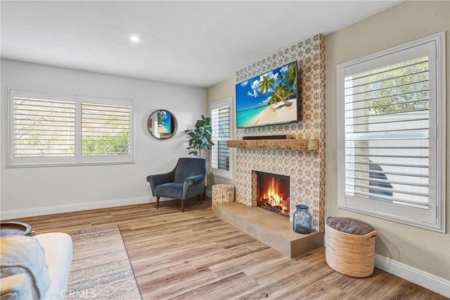 sitting room with a fireplace, wood finished floors, and a healthy amount of sunlight