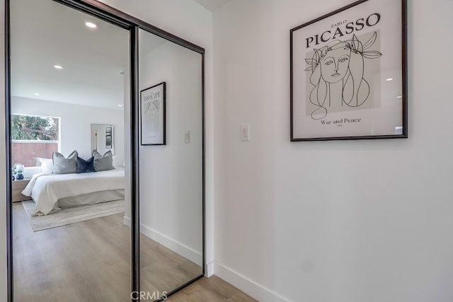 hallway with light wood-style flooring, baseboards, and recessed lighting