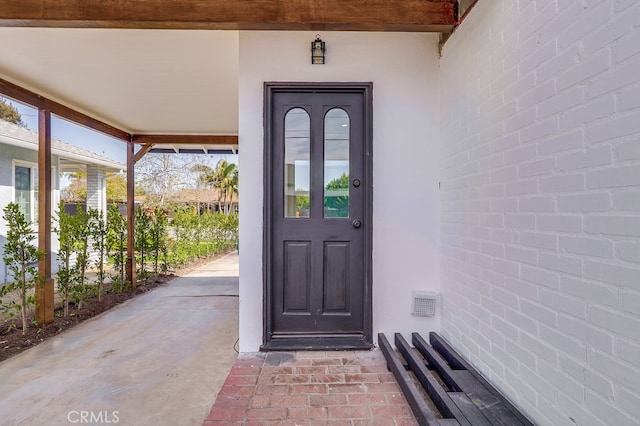 view of exterior entry with visible vents and stucco siding